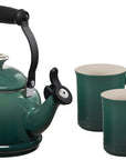 Green teakettle with black handle and two matching green mugs on a white background