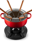 Le Creuset fondue set with a red enameled pot, black burner base, and six wooden-handled forks on a white background.