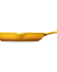 A bright yellow cast iron skillet with a single handle, shown in profile against a solid white background.