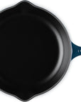 A top-down view of a cast iron skillet with a dark blue enameled handle and side handles, set against a plain white background.