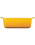 A rectangular yellow baking dish with side handles, shown from a front-facing perspective on a solid white background.