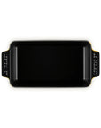 A black rectangular ceramic baking pan with side handles, featuring white printed measurement markings on the handles and a subtle gold accent along the rim, shown on a plain white background.