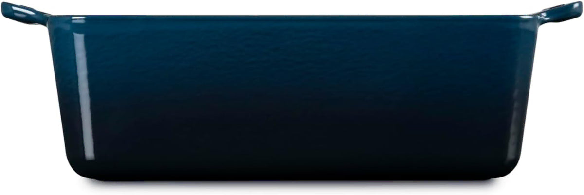 Side view of a rectangular dark blue enamel baking dish with side handles, shown on a clean white background.
