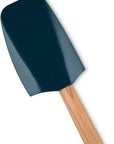 A silicone spatula with a dark teal-blue head and a light natural wood handle, shown diagonally on a plain white background.