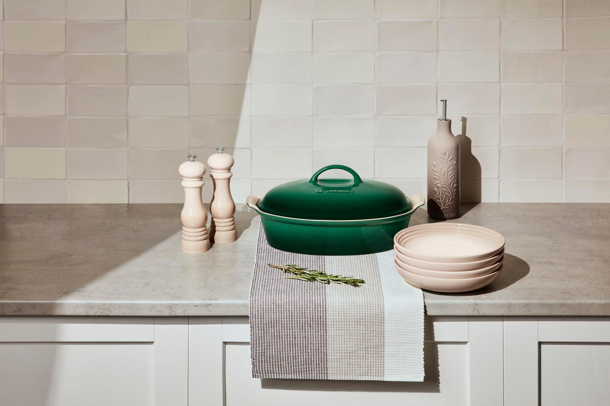 Artichaut casserole dish on a kitchen counter with a towel and herb.