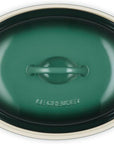 Le Creuset oval lidded casserole dish in dark green with cream-colored handles and rim, shown from a top-down perspective on a white background.