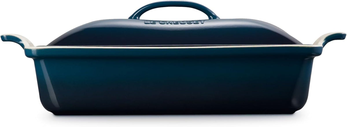 Side view of dark blue Le Creuset 4 qt Stoneware Heritage Covered Rectangular Casserole displayed on a white background