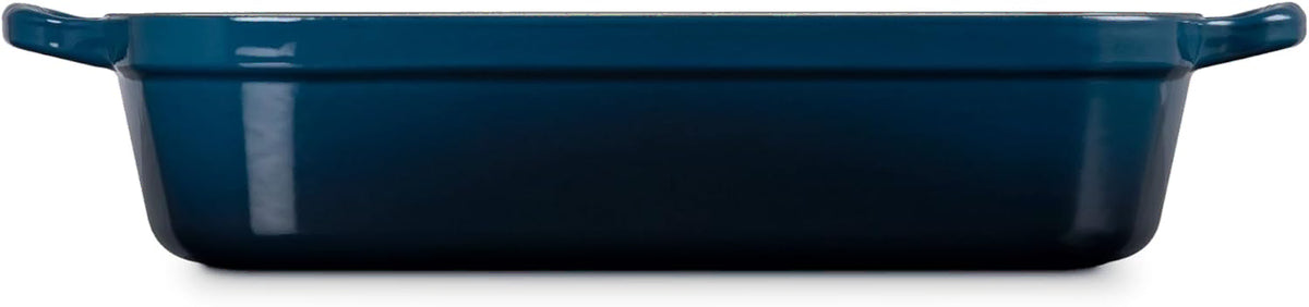 Side view of a dark blue rectangular baking dish with side handles, shown from a front angle on a white background.