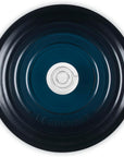 Top-down view of a Le Creuset round enameled cast iron pot with side handles, showing a dark navy blue exterior and a silver metal center knob.