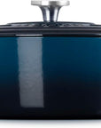 Side view of a dark blue enameled cast iron Dutch oven with a matching lid and silver metal knob, shown on a clean white background.