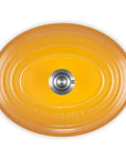 An oval yellow enameled cast iron Dutch oven lid with side handles and a central silver metal knob, photographed from a top-down perspective on a white background.