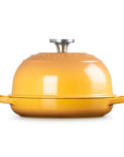 A yellow enameled cast iron casserole dish with a matching lid and side handles, photographed on a clean white background.