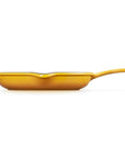 A yellow cast iron skillet with a long handle, shown from a side profile view against a solid white background.