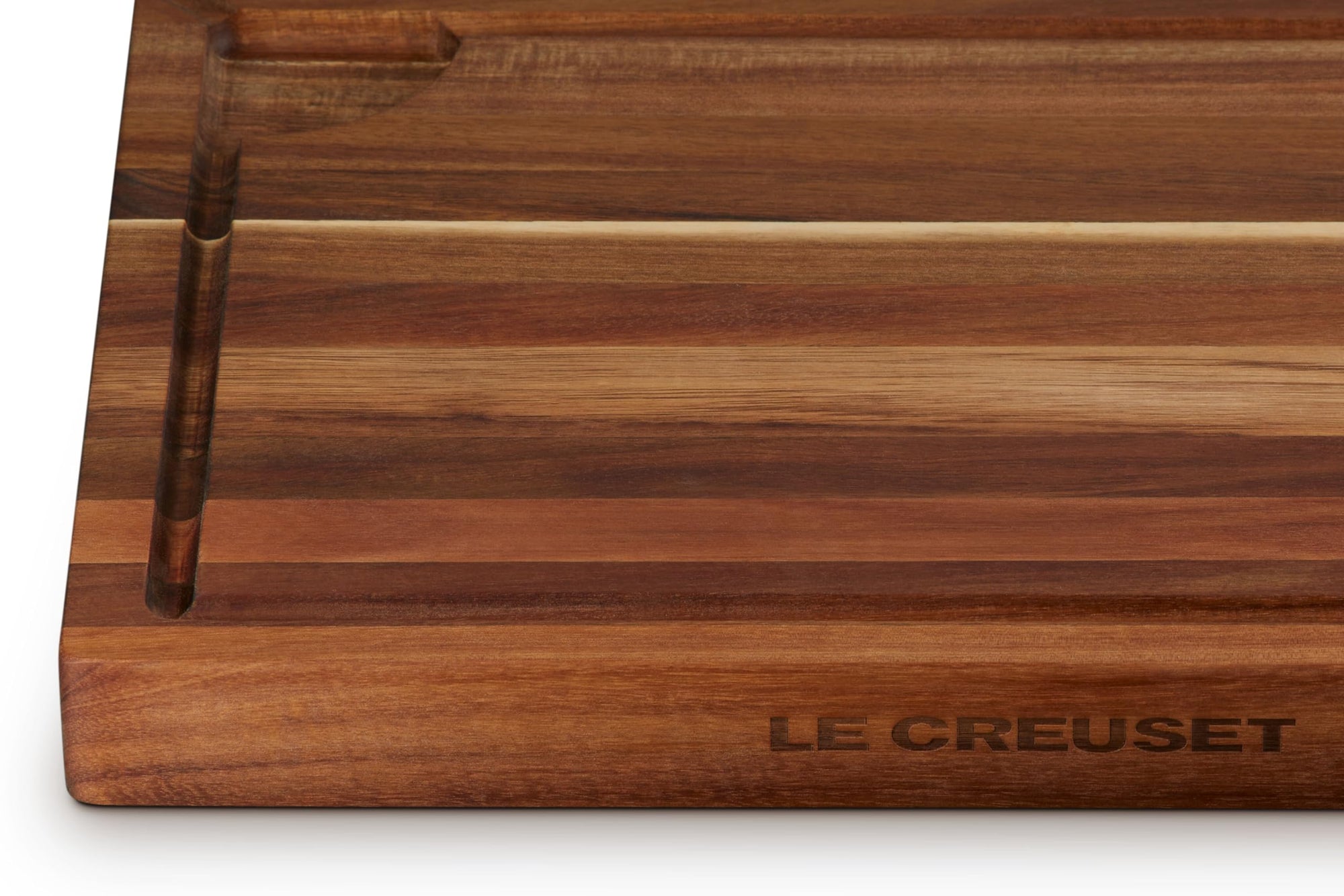 Close up of logo on wooden cutting board with 'Le Creuset' branding on a white background