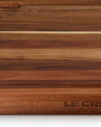 Close up of logo on wooden cutting board with 'Le Creuset' branding on a white background