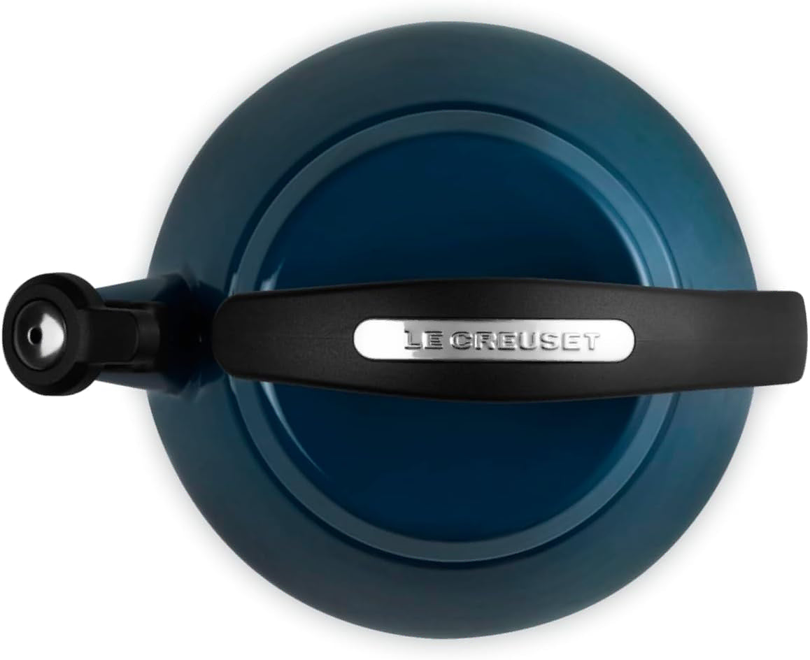 Top-down view of a Le Creuset enameled cast iron kettle in a deep teal blue color, featuring a black handle with a silver brand plate.