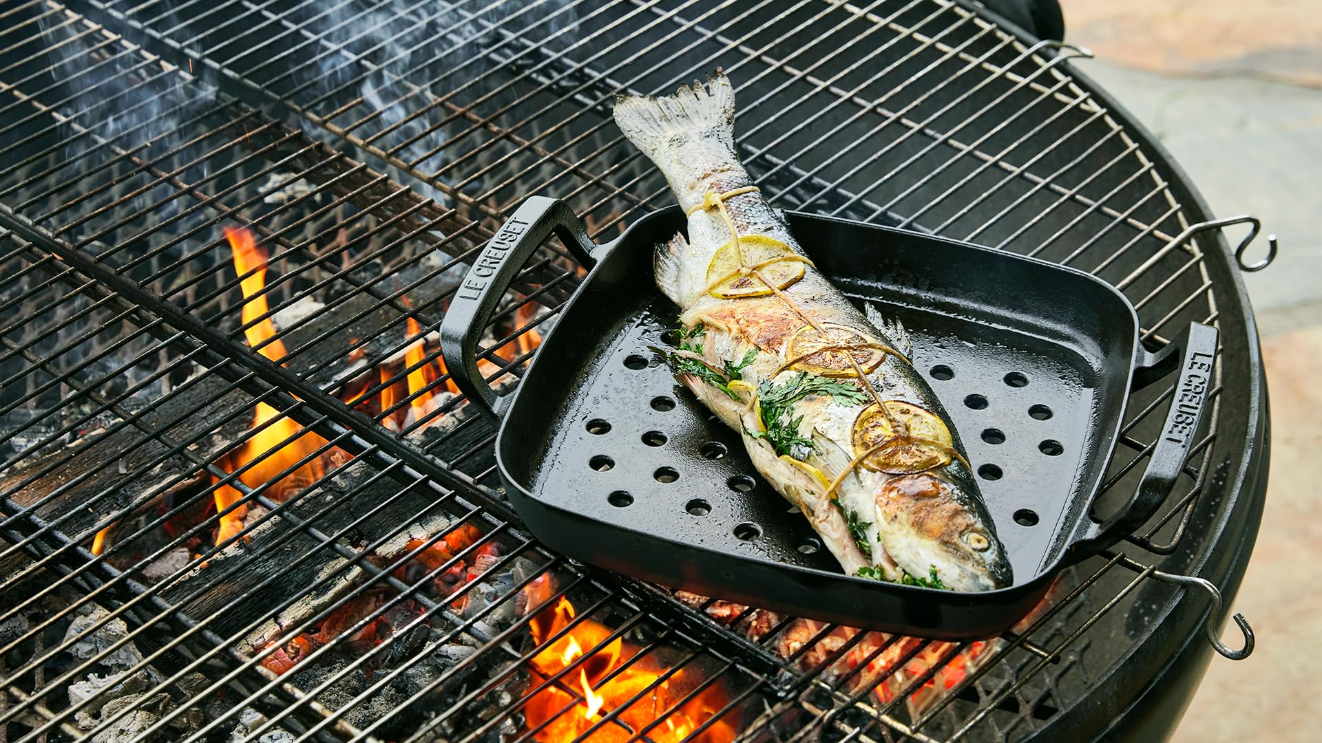 Fish being grilled on a barbecue with flames visible