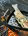 Fish being grilled on a barbecue with flames visible