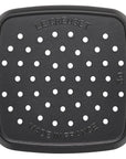 Black grill pan with holes and 'Le Creuset' branding on a white background