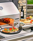 Outdoor pizza oven with a pizza being cooked, surrounded by outdoor furniture and decor.