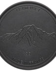 Black cast iron skillet with mountain design and 'Le Creuset' branding on a white background