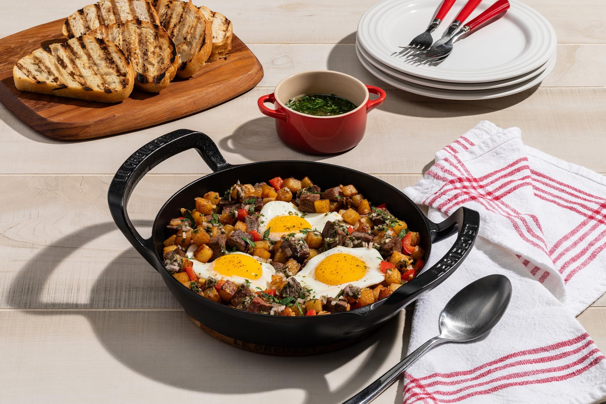 Breakfast dish with eggs and vegetables in a skillet on a wooden table.
