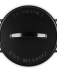 A black Le Creuset round lidded pot shown from a top-down view on a white background, featuring embossed branding and the text 'MADE IN FRANCE'.
