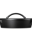 A black cast iron Dutch oven with a lid and integrated top handle, shown from a front three-quarter angle on a solid white background.