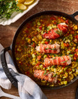 Lobster tail dish with vegetables in a cast iron skillet on a wooden table.