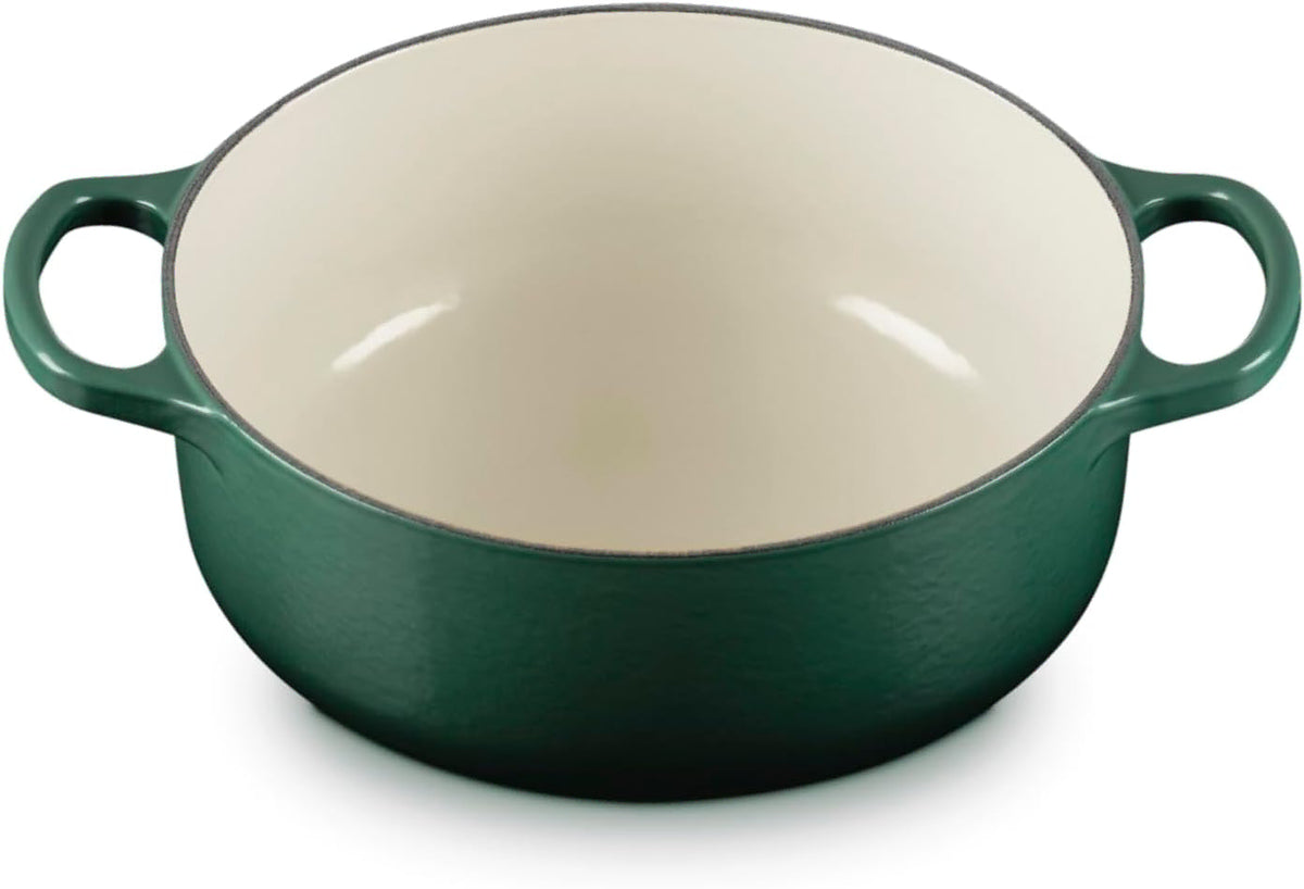 A dark green enameled cast iron Dutch oven with a cream-colored interior and side handles, shown on a white background.
