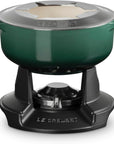 Le Creuset enameled cast iron pot with handles and a lid, shown on a black burner base against a white background.