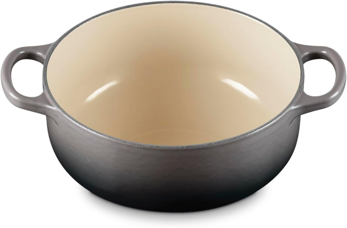 A round enameled cast iron Dutch oven with a dark gray exterior and a warm cream-colored interior, featuring two side handles.