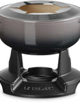 Le Creuset enameled cast iron pot with lid, shown on a black metal burner stand against a white background.