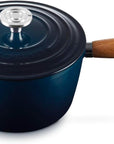 A dark blue enameled cast iron saucepan with a matching lid and a brown wooden handle, shown on a white background.