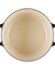 Round enameled cast iron skillet with black handles on a white background