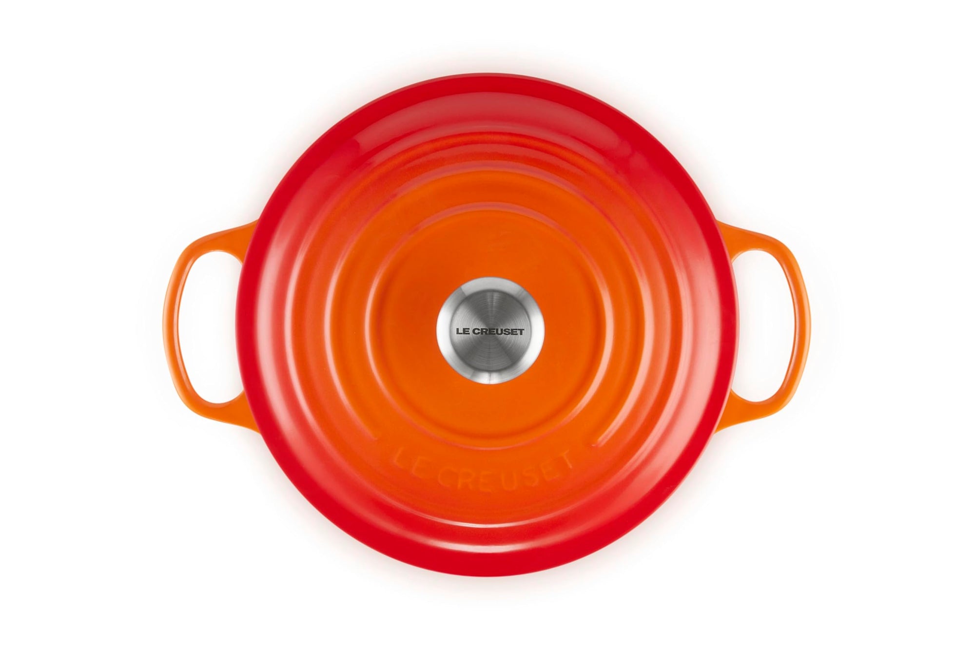 Orange round Le Creuset pot with handles on a white background