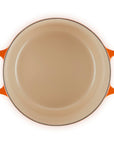 Round beige dish with orange handles on a white background