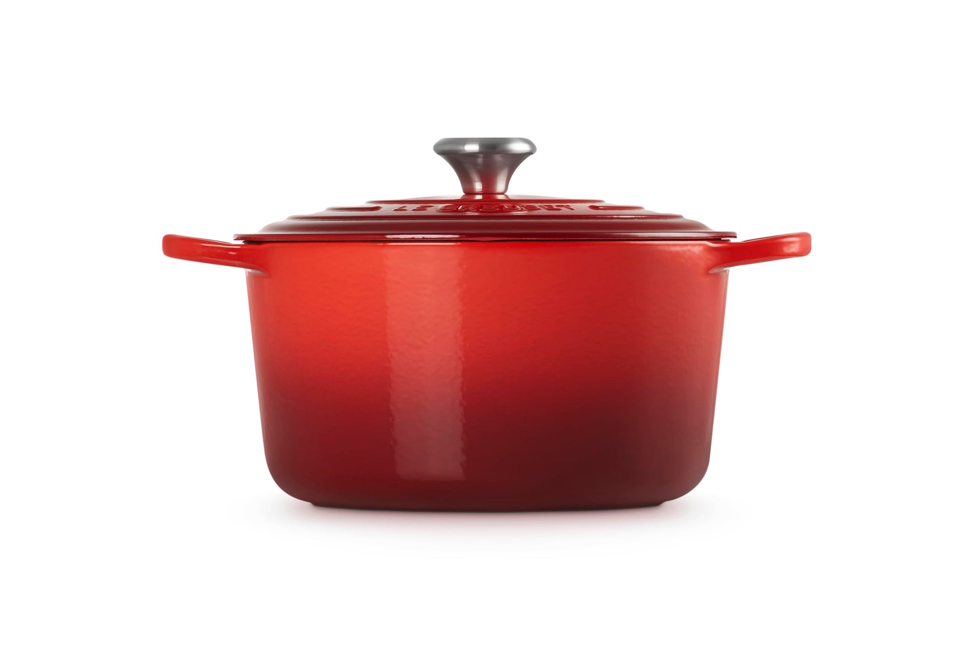 Red enameled cast iron Dutch oven with a lid on a white background