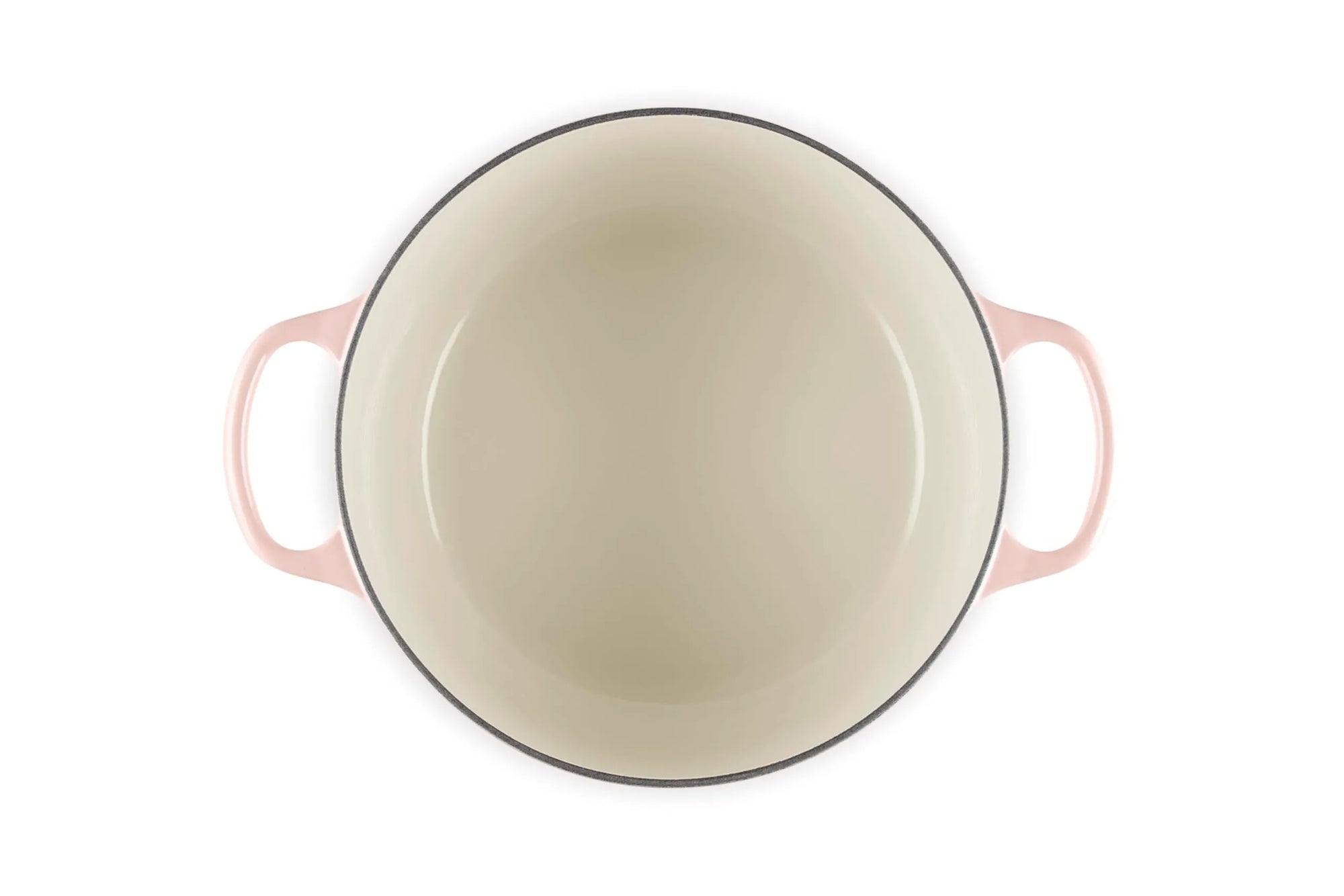 A top-down view of a round enameled cast iron Dutch oven with a pale pink exterior and a cream-colored interior, featuring two side handles.