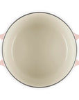 A top-down view of a round enameled cast iron Dutch oven with a pale pink exterior and a cream-colored interior, featuring two side handles.