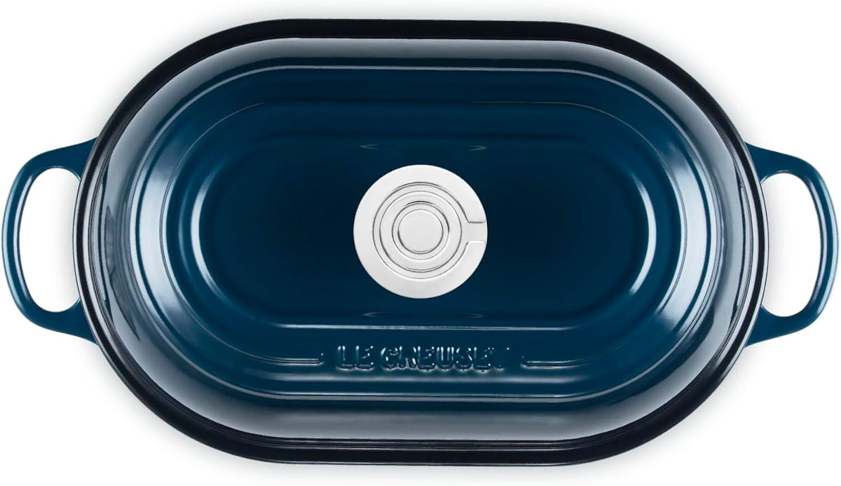 Top view of a Le Creuset oval roasting pan in a deep navy blue color, shown from a top-down perspective on a white background.