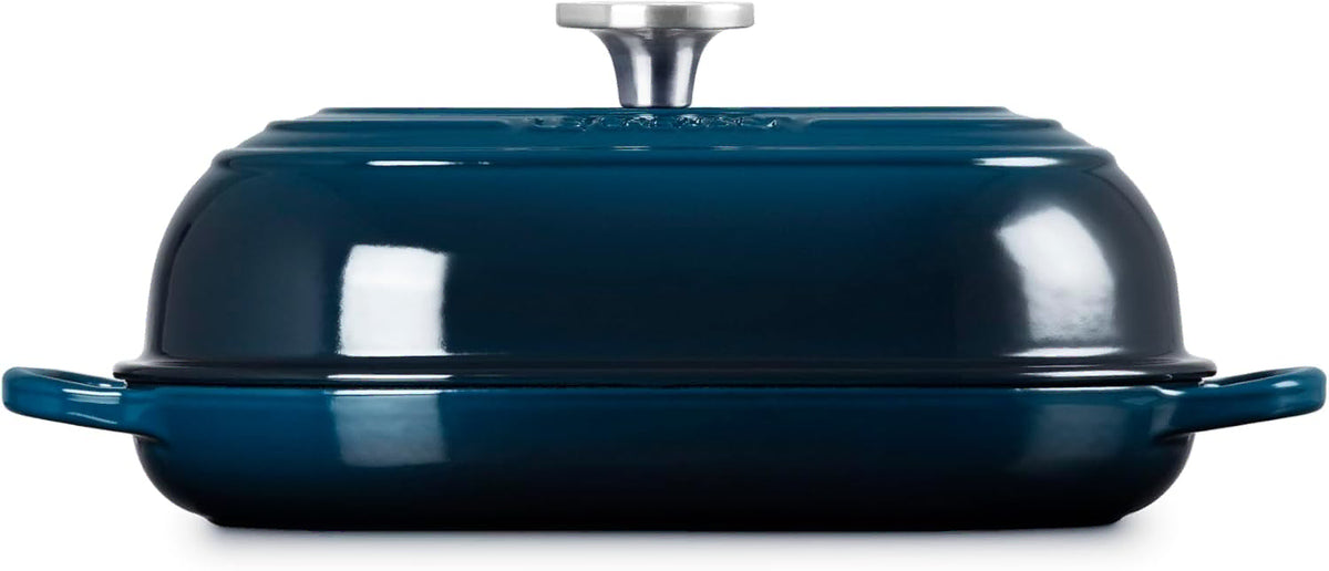 Side view of a dark teal enameled cast iron Dutch oven with a matching lid and silver metal knob, shown on a clean white background.