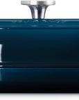 Side view of a dark teal enameled cast iron Dutch oven with a matching lid and silver metal knob, shown on a clean white background.