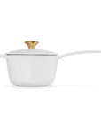 White saucepan with a gold lid knob on a white background