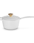 White enameled cast iron cookware with a gold lid knob on a white background