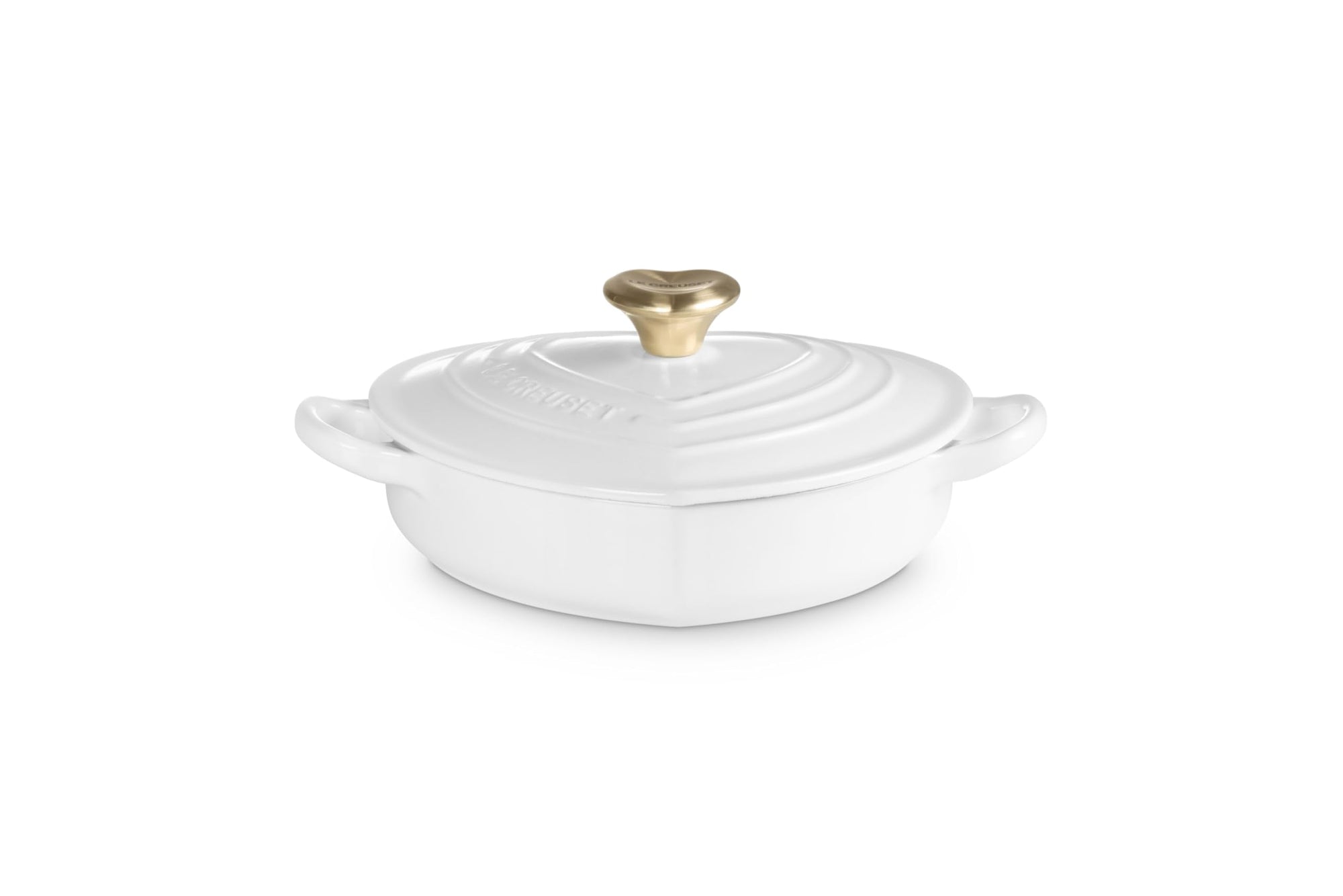 Side view of white heart shaped 1.25 qt cocotte with handles and a light gold heart knob displayed on a white background