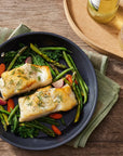 Top view of Le Creuset Essential Non-stick Ceramic 8" Fry Pan with cooked fish and vegetables next to drinks and a sauce on a wooden surface