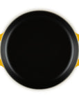 A top-down view of a round black cast iron skillet with bright yellow handles, isolated on a white background.