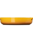 A bright yellow rectangular baking dish with two small side handles, shown from a front-facing perspective on a solid white background.