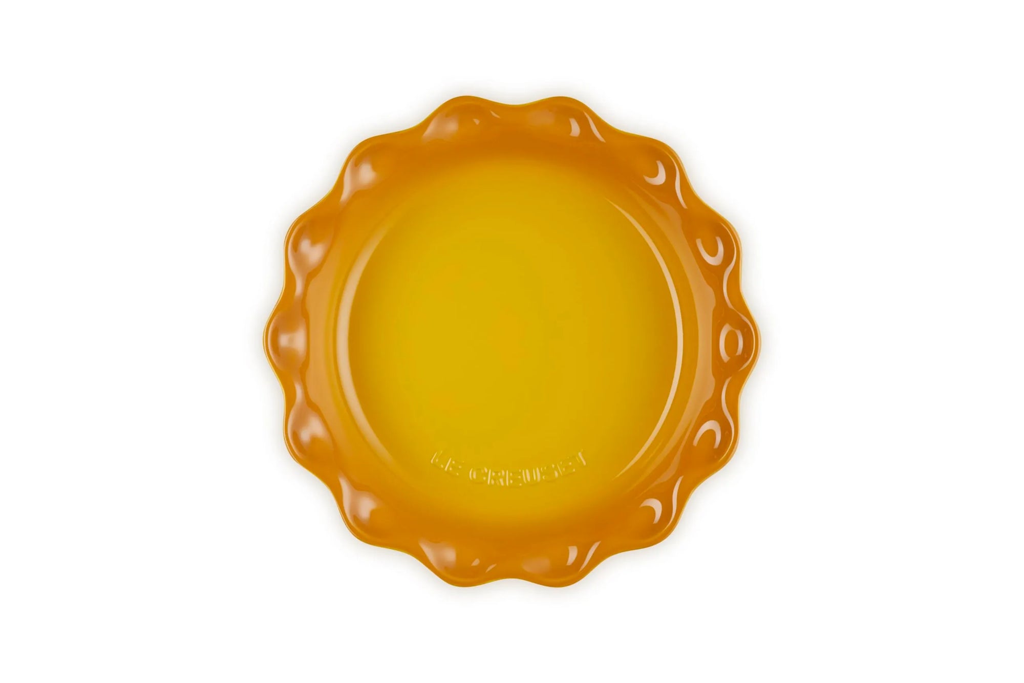 A small scalloped ceramic plate in a vibrant yellow-orange color, photographed from directly above on a clean white background.